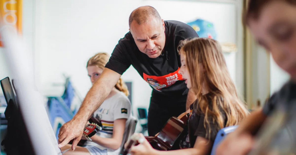 Taso's Music School instructor teaching private guitar lesson in a modern Surfers Paradise studio.