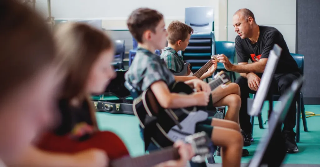 Small group guitar class of four students practicing chords together in a Surfers Paradise music studio.