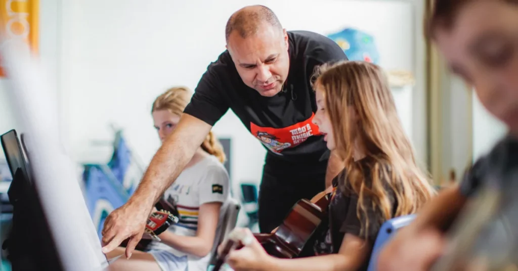 Taso, the qualified music teacher at Taso's Music School Surfers Paradise, provides direct, hands-on guitar guidance to students in a small group class.